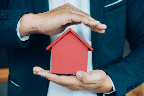 business-man-hand-hold-the-house-model-saving-small-house